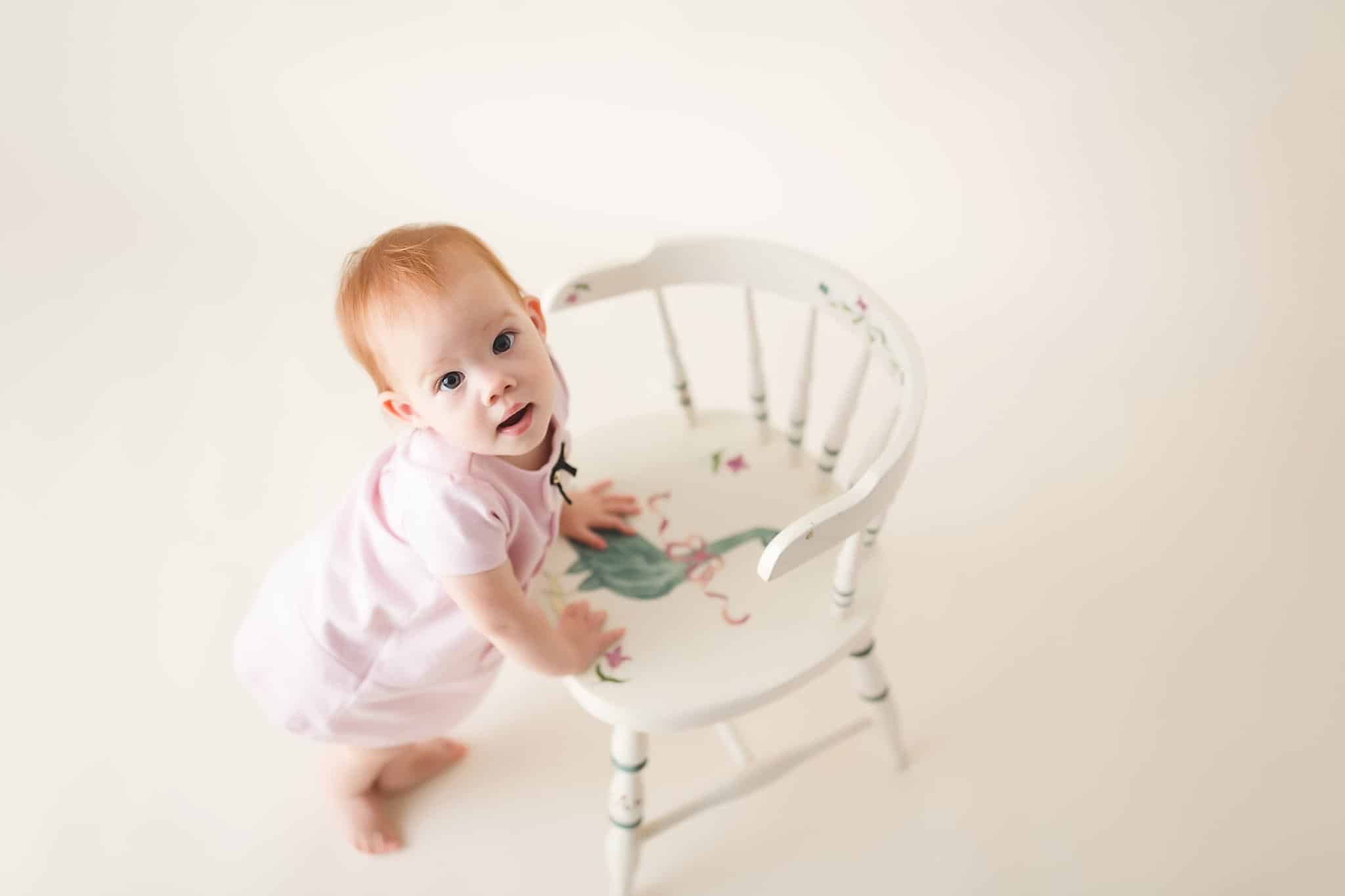 toddler girl sitting white chair cream background 1st Birthday Pics Jacksonville