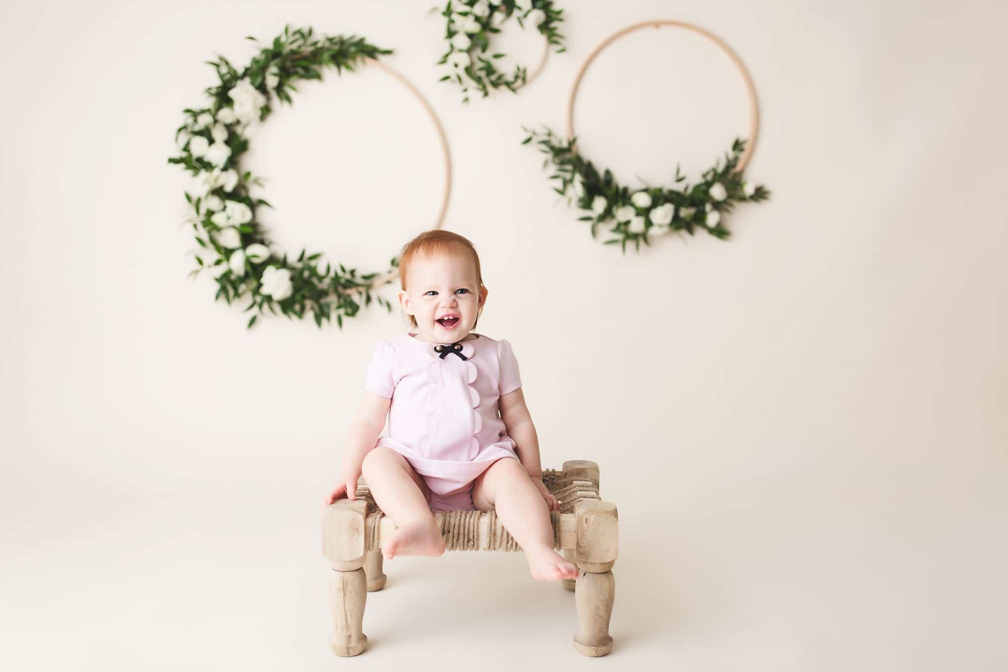 1st Birthday Pics Jacksonville toddler girl sitting white chair cream background floral wreaths