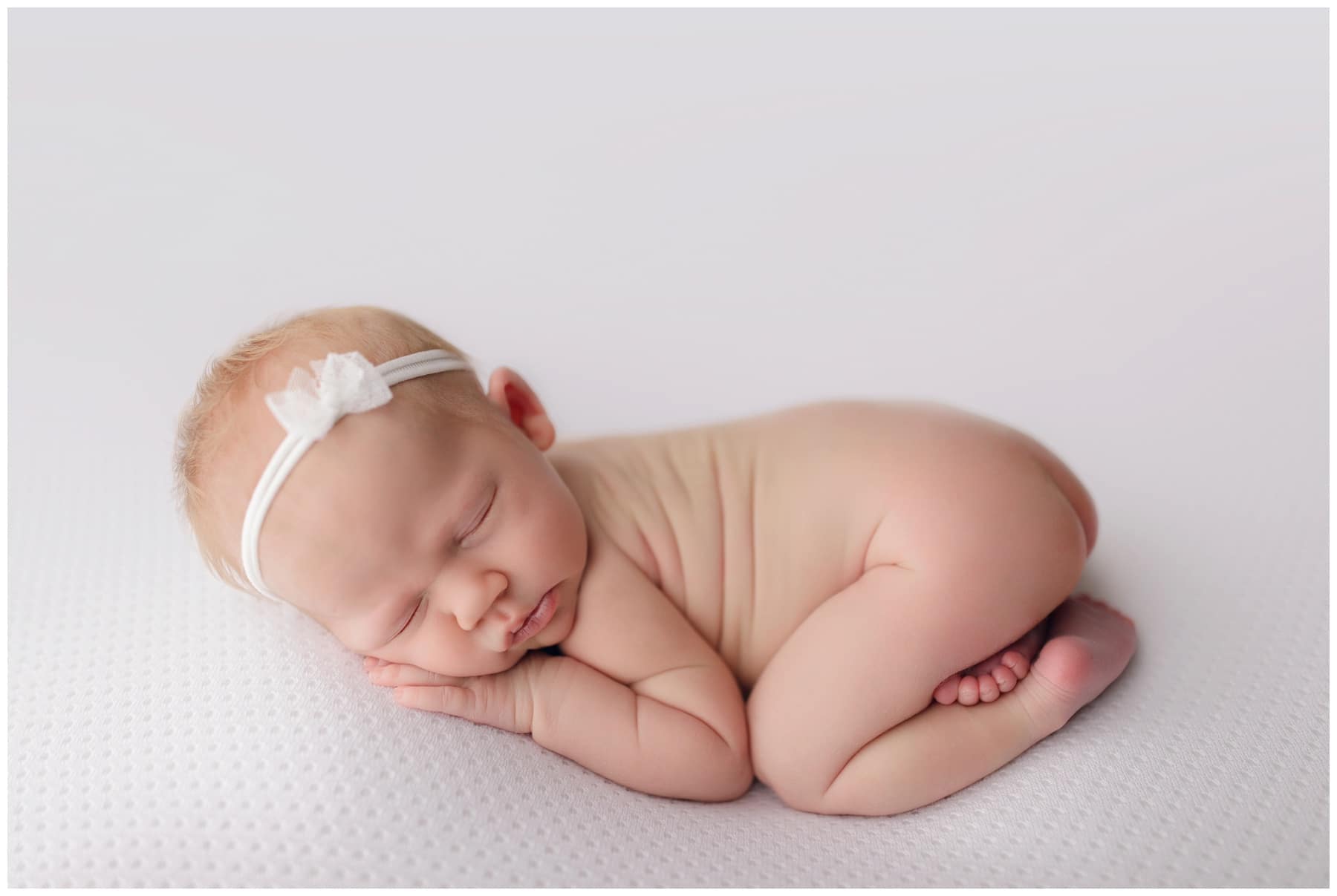 new baby photos ginger baby girl sleeping on whtie backdrop with simple white bow