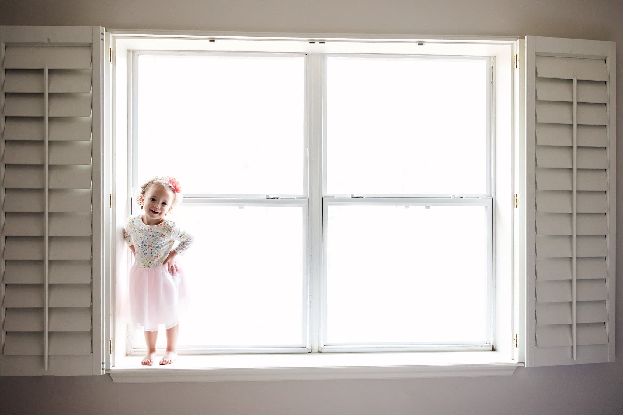 St Augustine Lifestyle Photographer little girl dancing in window of parents bedroom window. beautiful backlight