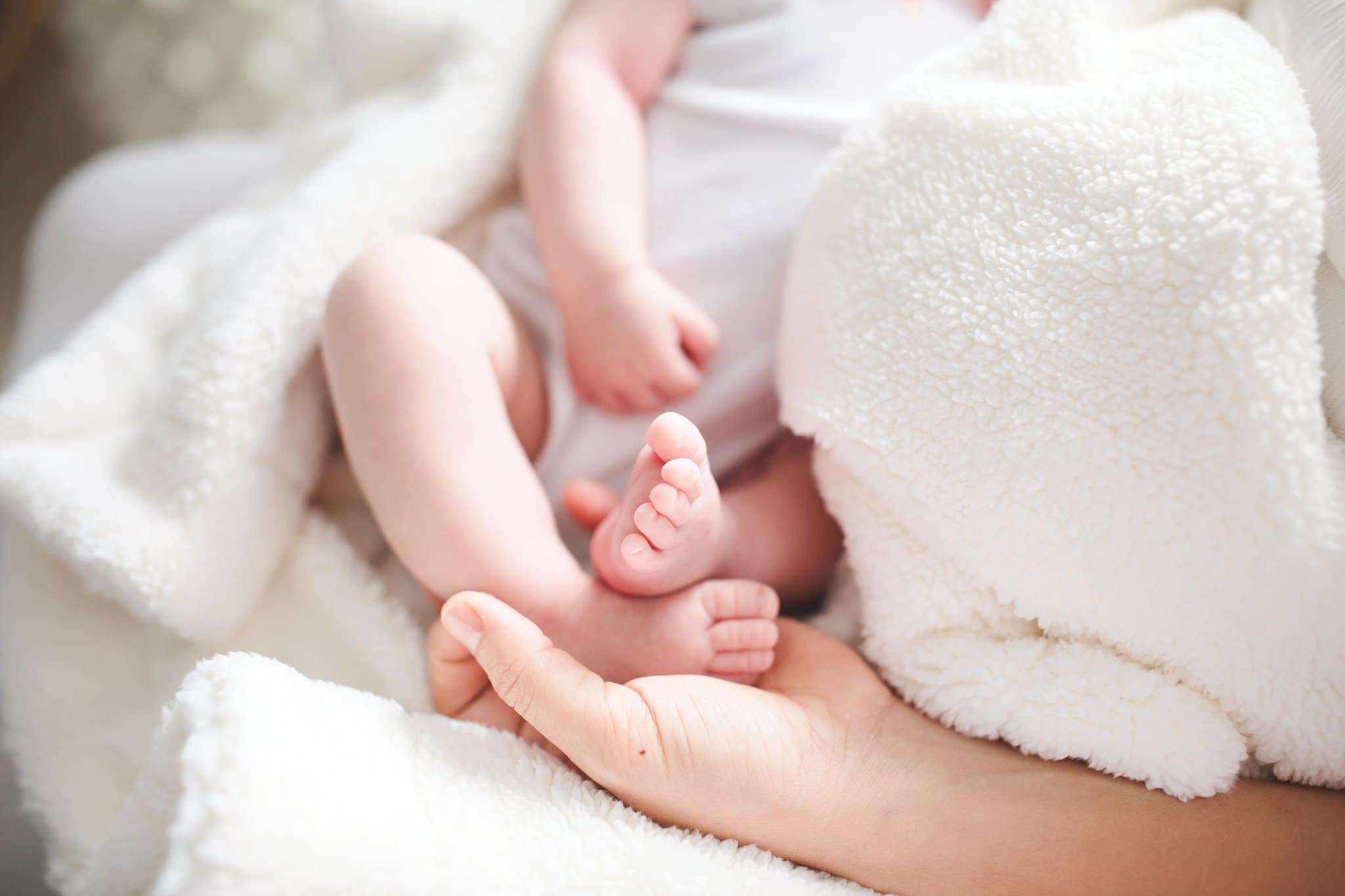 In Home Newborn Photography newborn baby toes in mom's hands surrounded by white