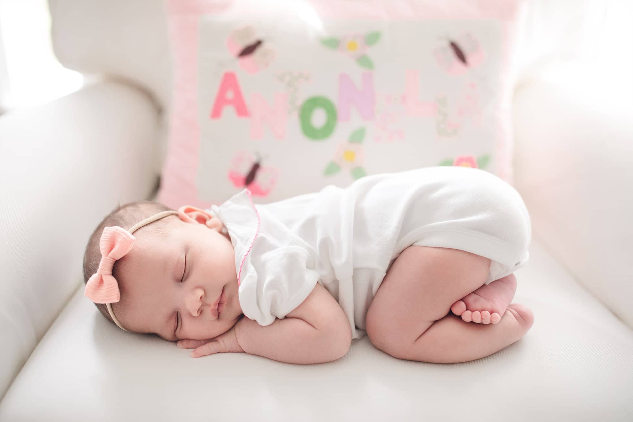 newborn baby girl pink bow sleeping on belly