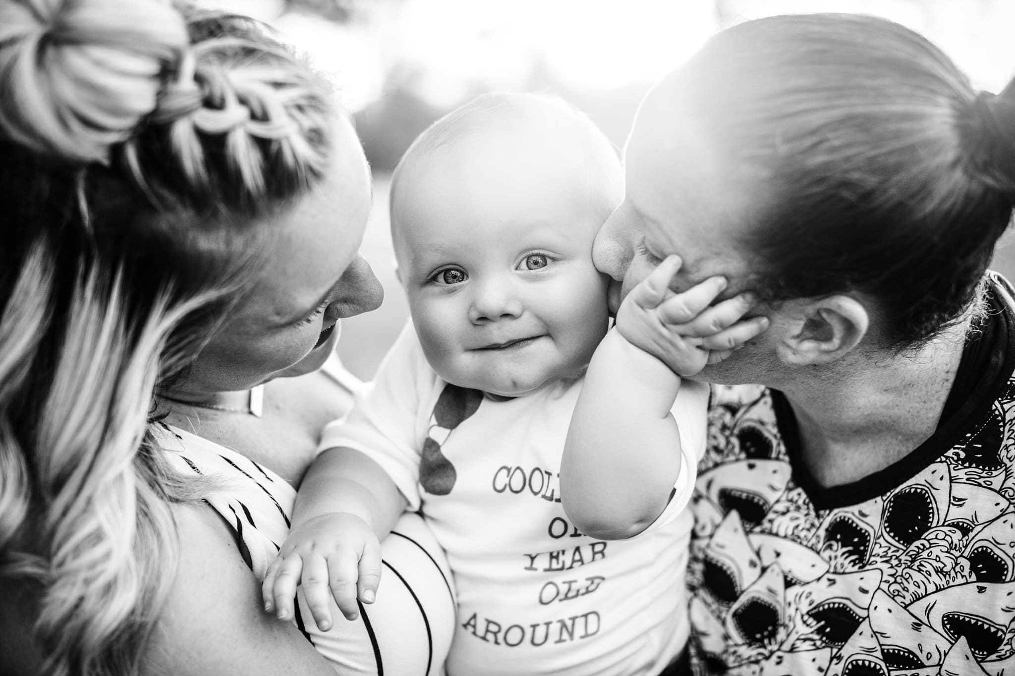 One year old toddler being hugged by his two moms chubby hand on moms face backlight One Year Photos in Jacksonville black and white