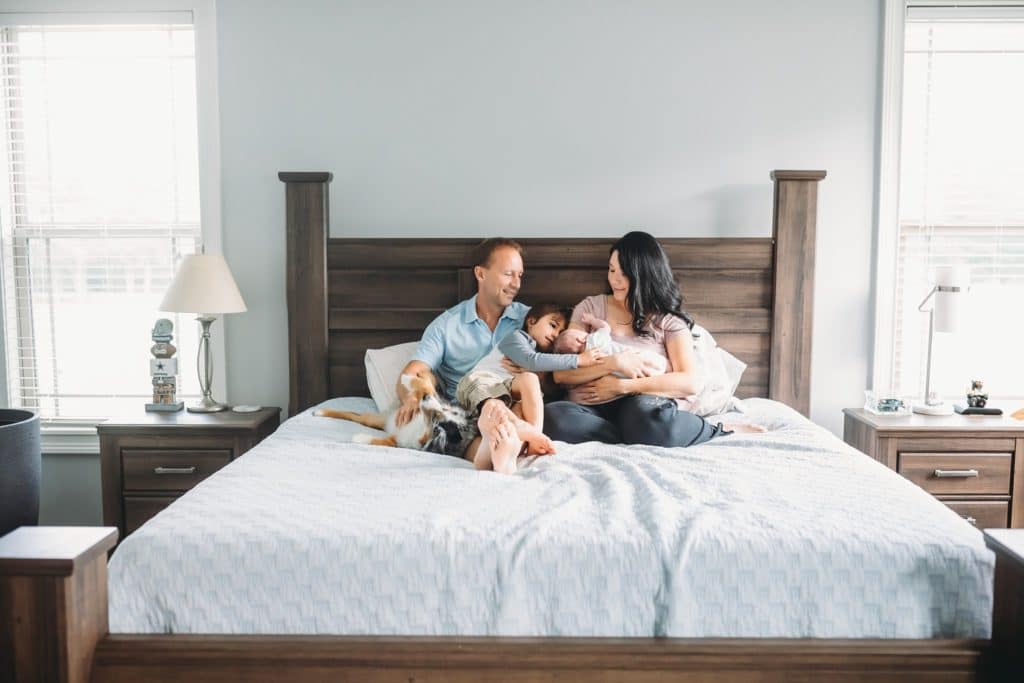 lifestyle baby photography mom dad big brother and newborn baby snuggling in bed