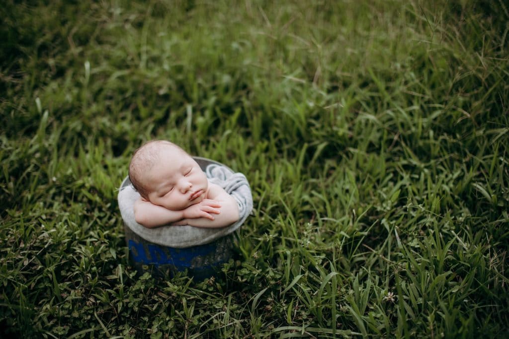 lifestyle baby photography chunky baby boy posed in vintage bucket in grassy yard