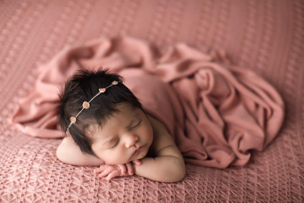Jacksonville Photographer newborn studio photography session beautiful baby girl with head full of dark hair on coral blanket