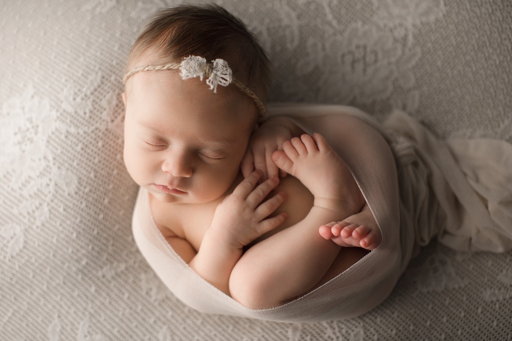 newborn baby girl sleeping on cream lace blanket