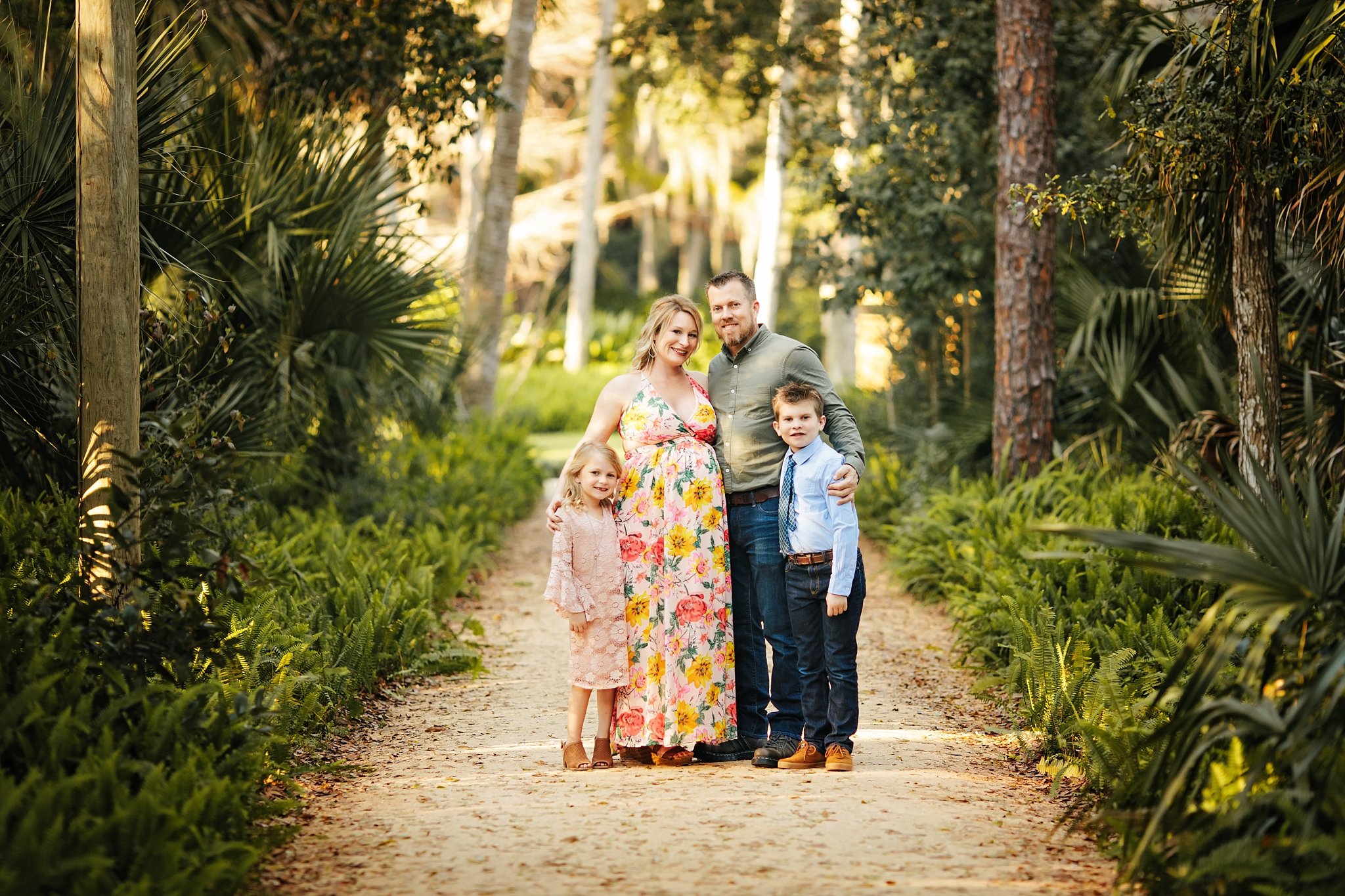 St Augustine Maternity Photographer Washington Oaks Gardens State Park Family of 4 pregnant mom in long floral dress standing on woodsy path