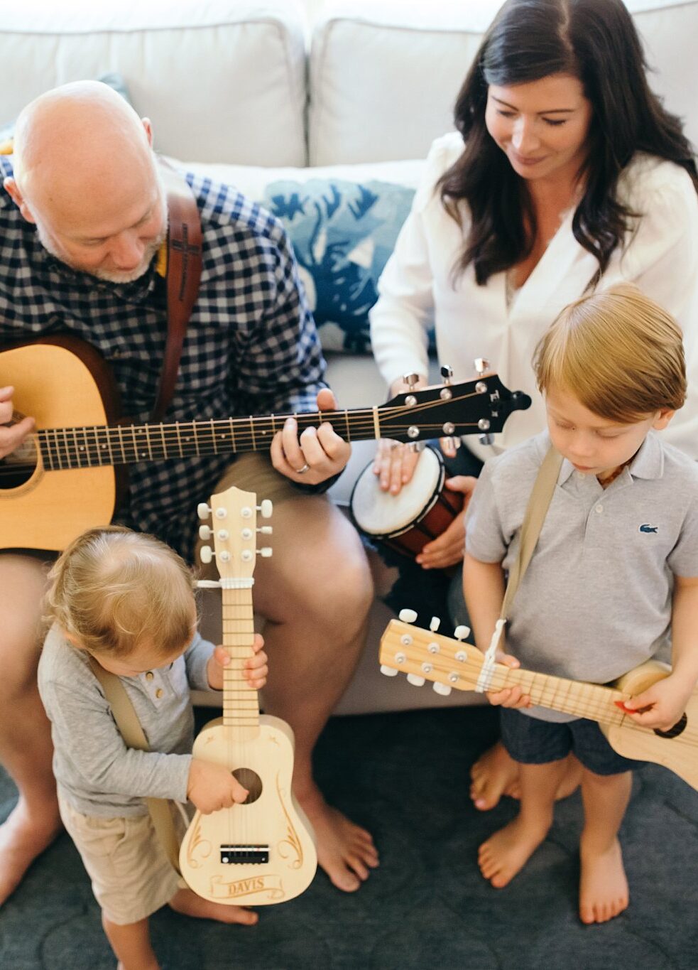 Family of 4 with 2 little boys playing instruments in living room