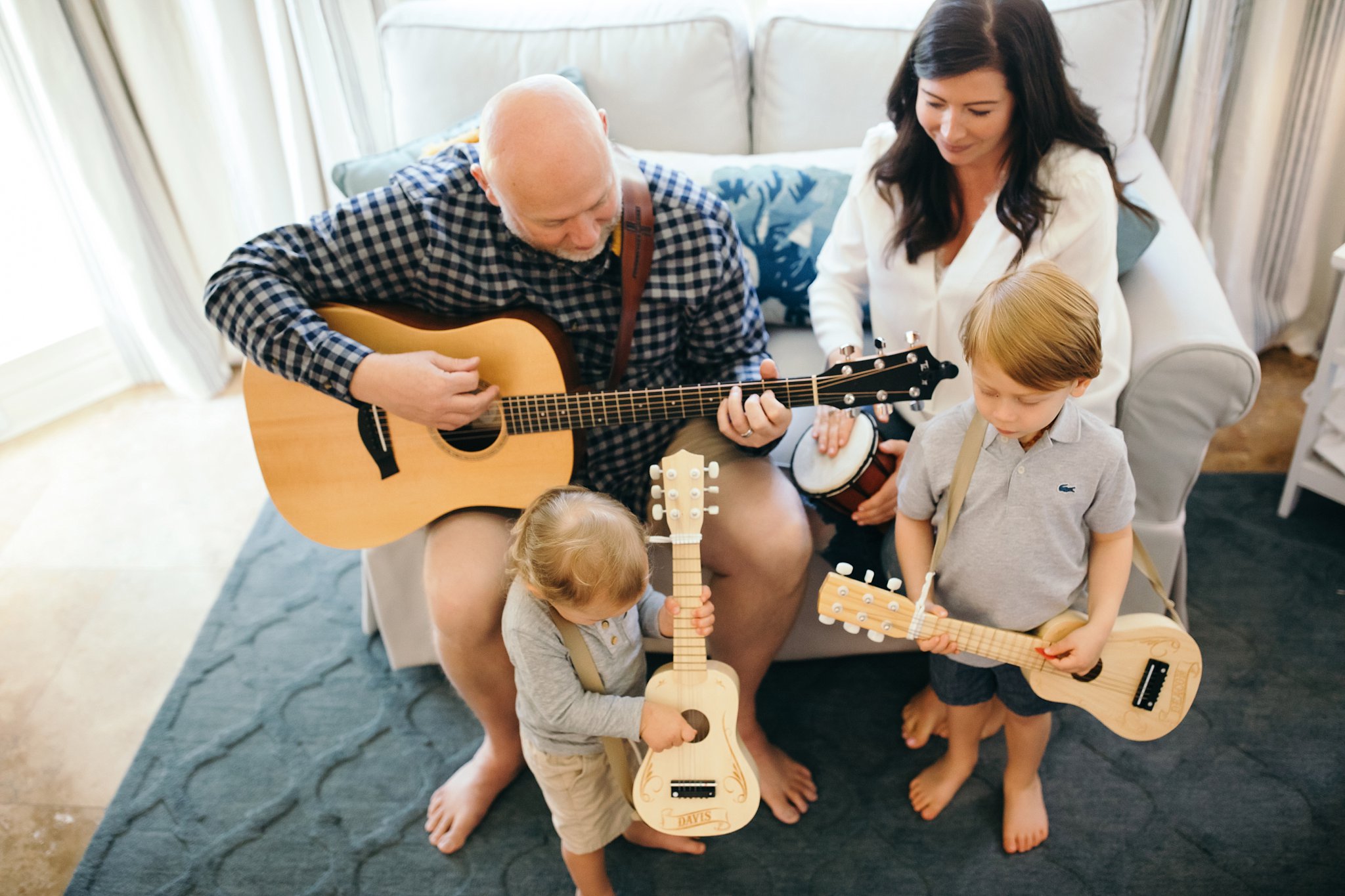 Family of 4 with 2 little boys playing instruments in living room