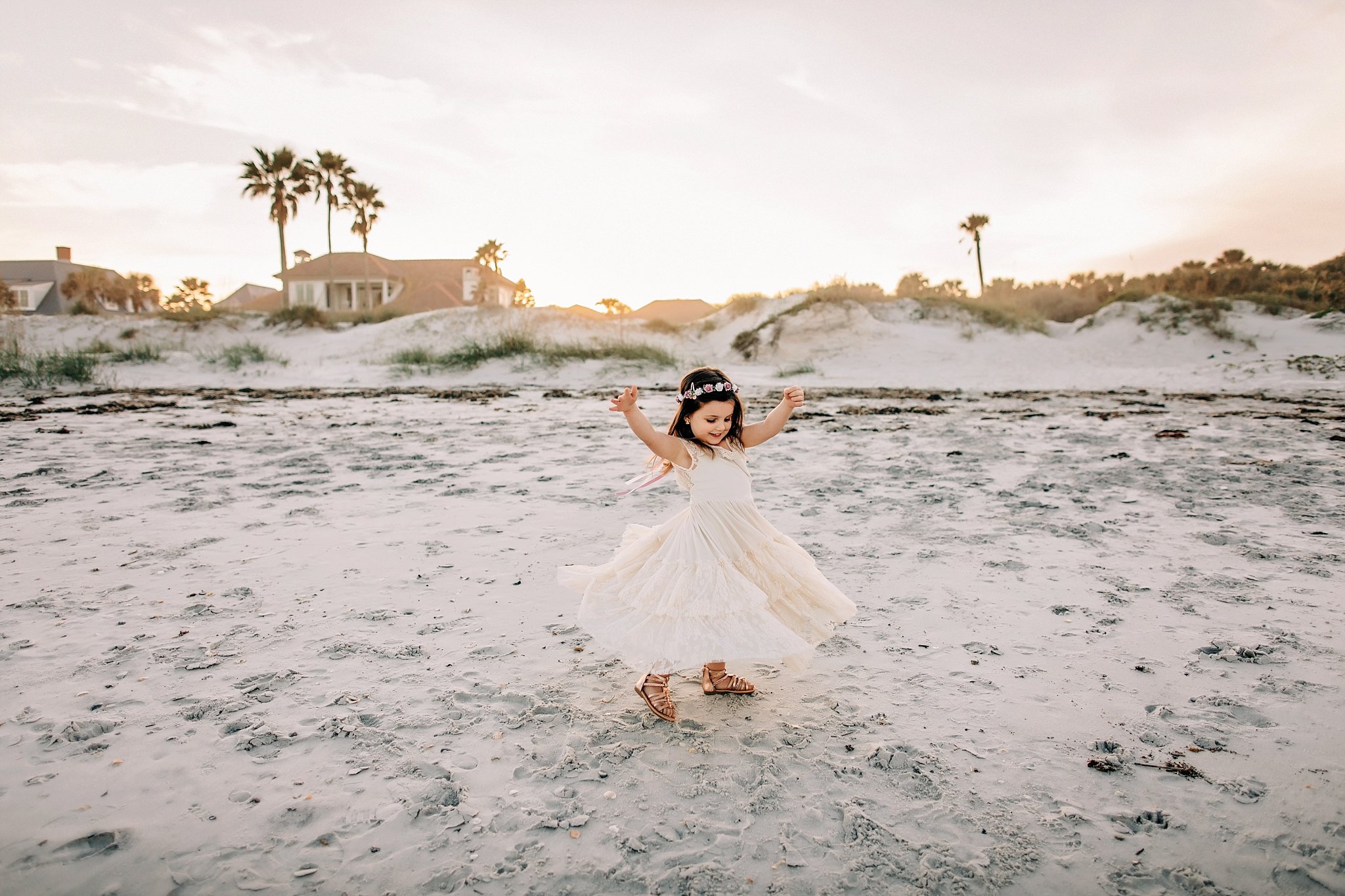 Beach Photos in Ponte Vedra little girl twirling on the beach in cream dress and flower crown