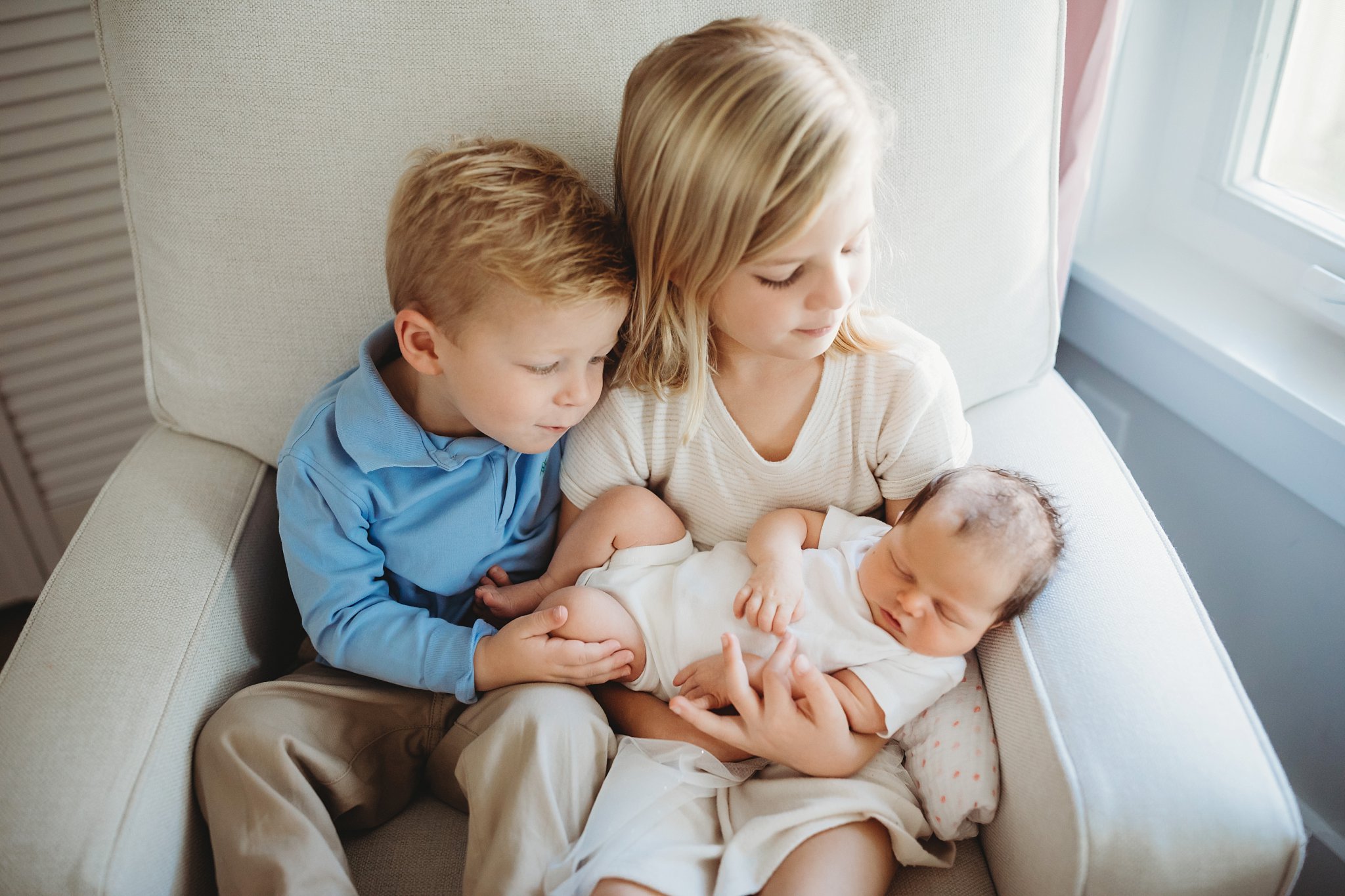 Siblings holding newborn baby