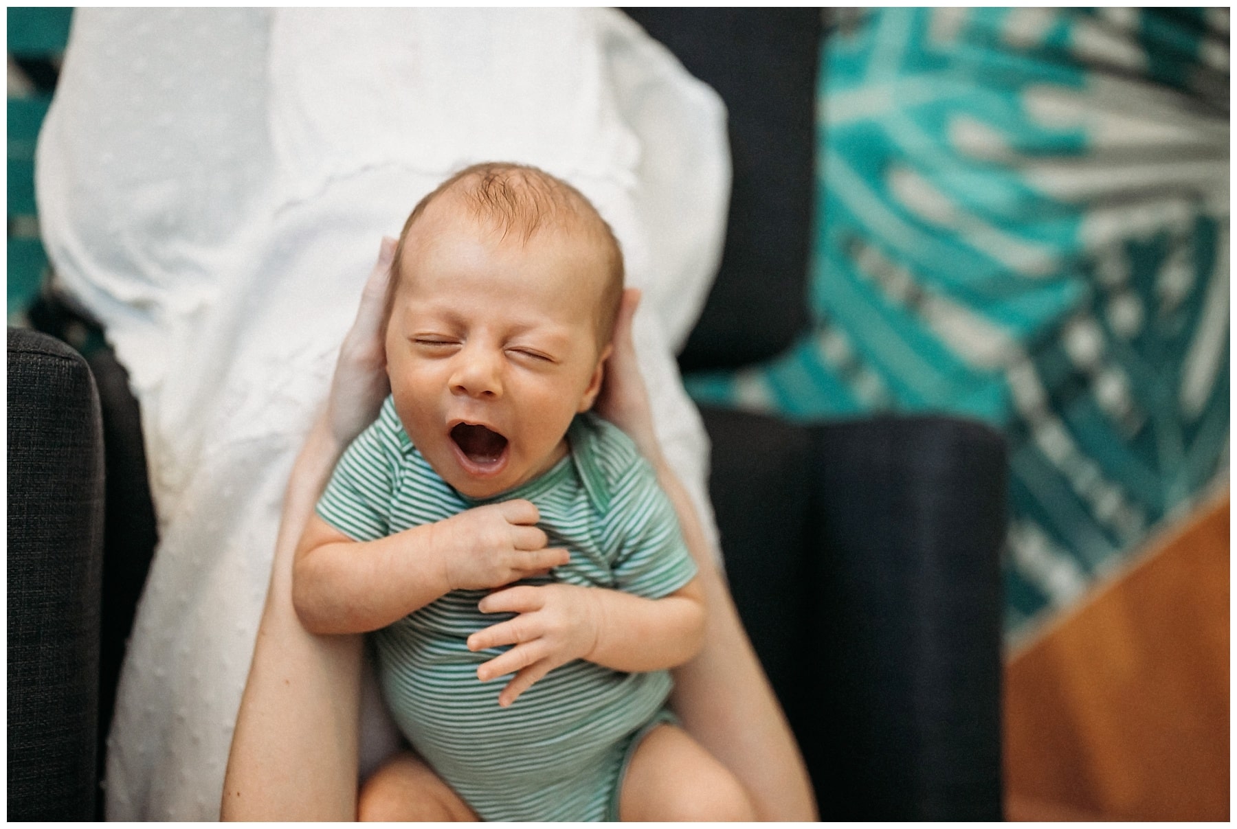 6 week old baby boy yawning in green striped onesie
