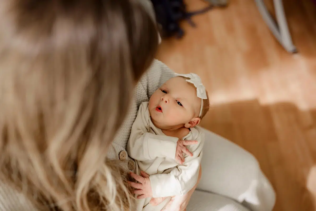 Hospital newborn photography Jacksonville – newborn making cute fave while cradled in mother’s arms