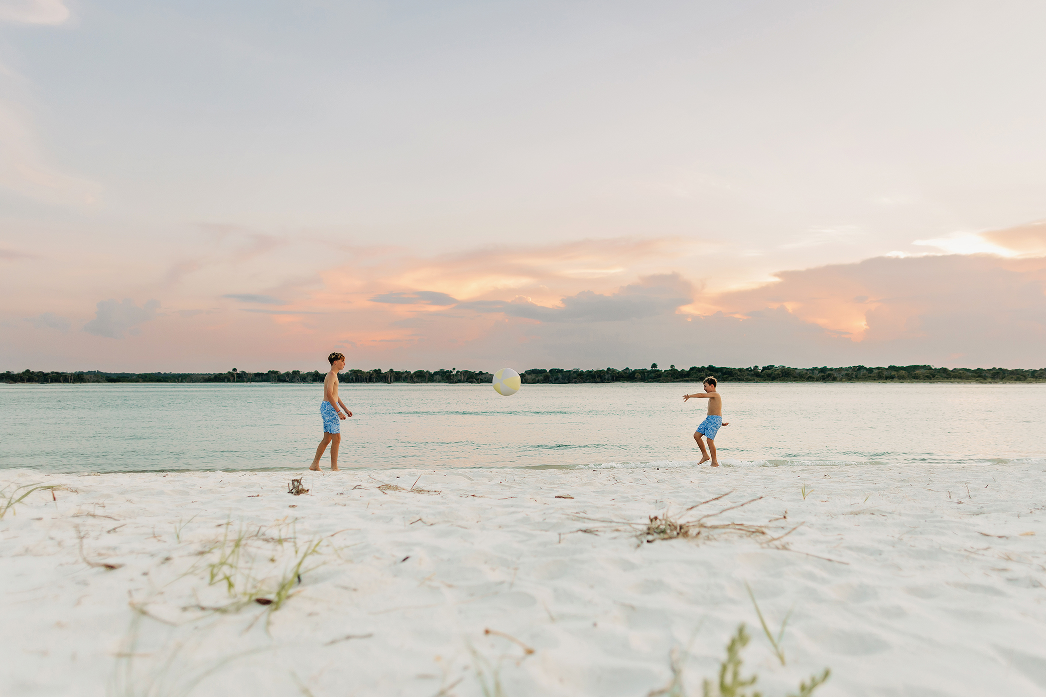 Two brothers playing with a beach ball beside the water during their family photography session