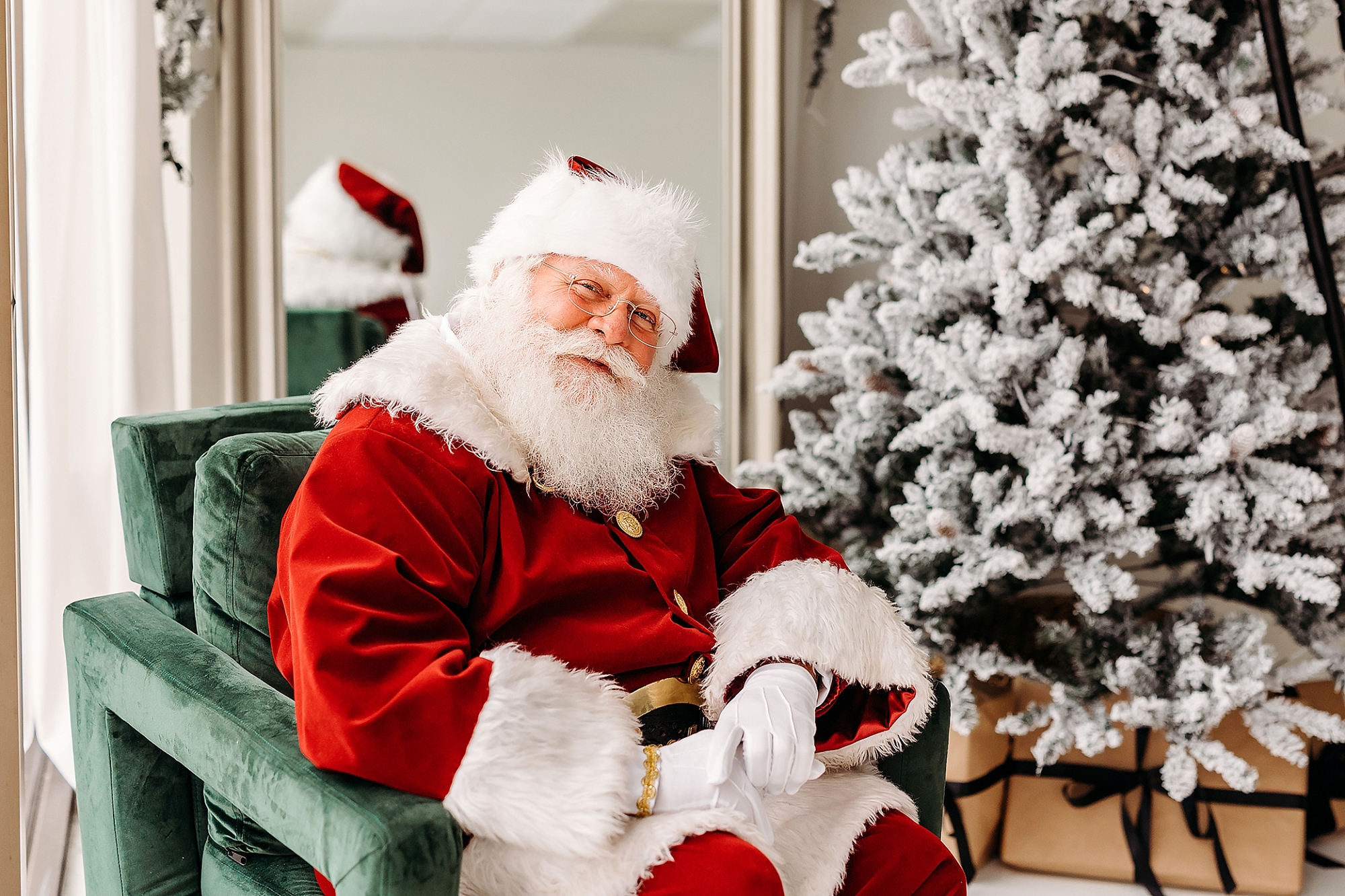 Santa Claus Ron seated in a green velvet chair beside a flocked Christmas tree